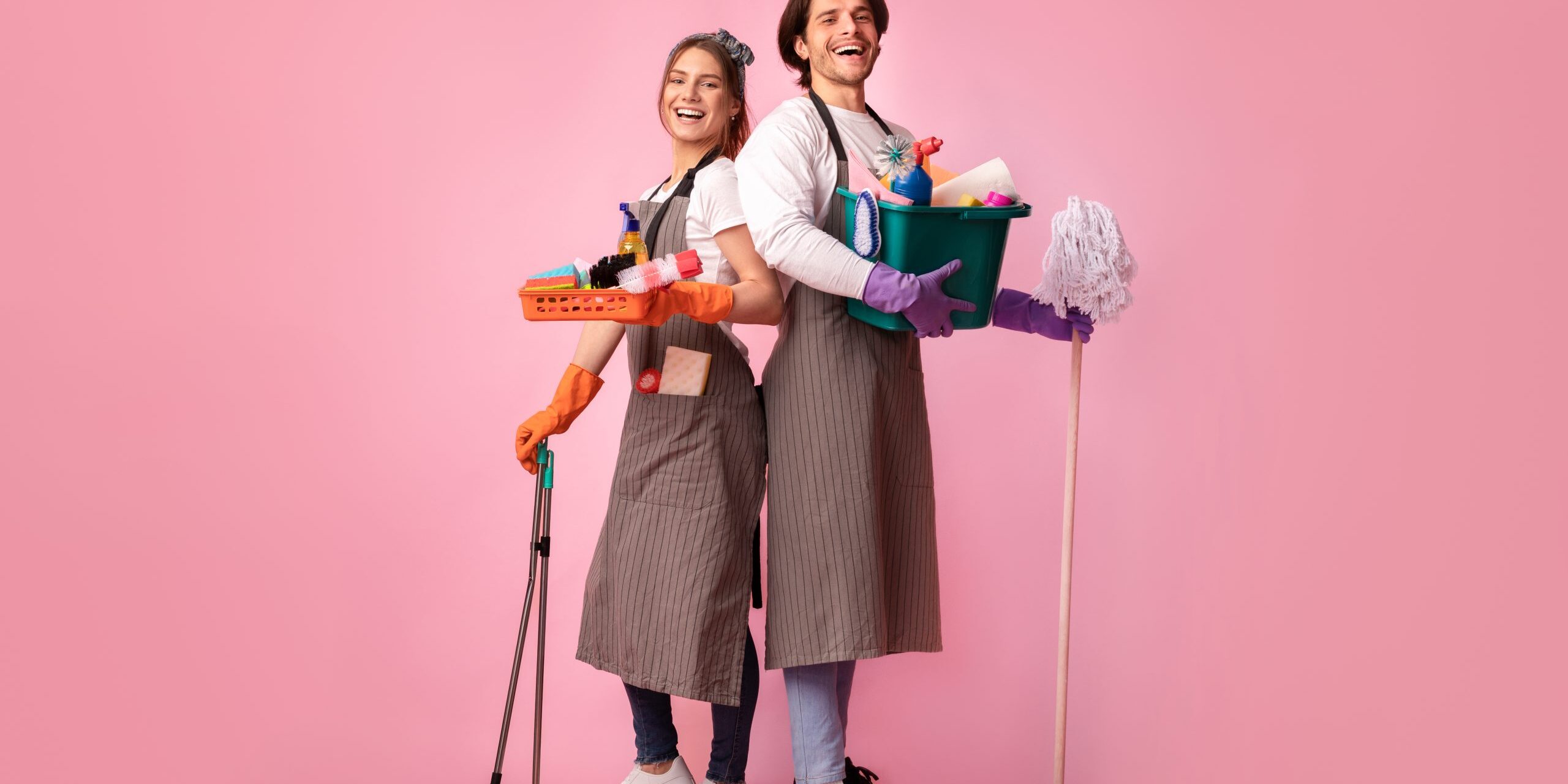 Happy young couple with lots of detergents posing over pink background